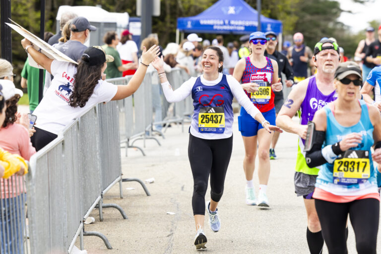 A Boston Marathon runner high-fiving a spectator