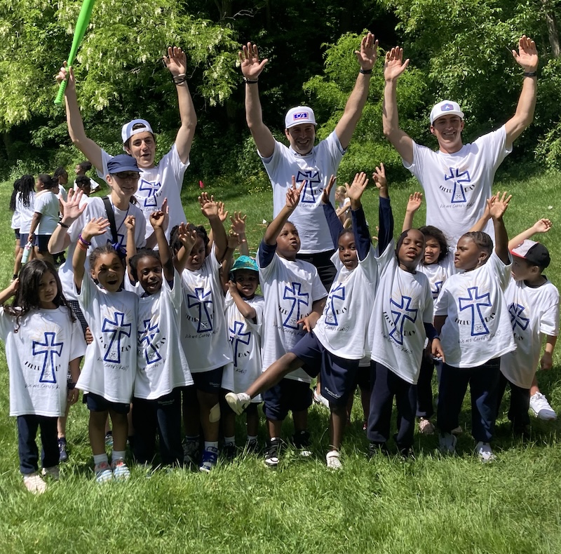 Teen volunteers with children at park.