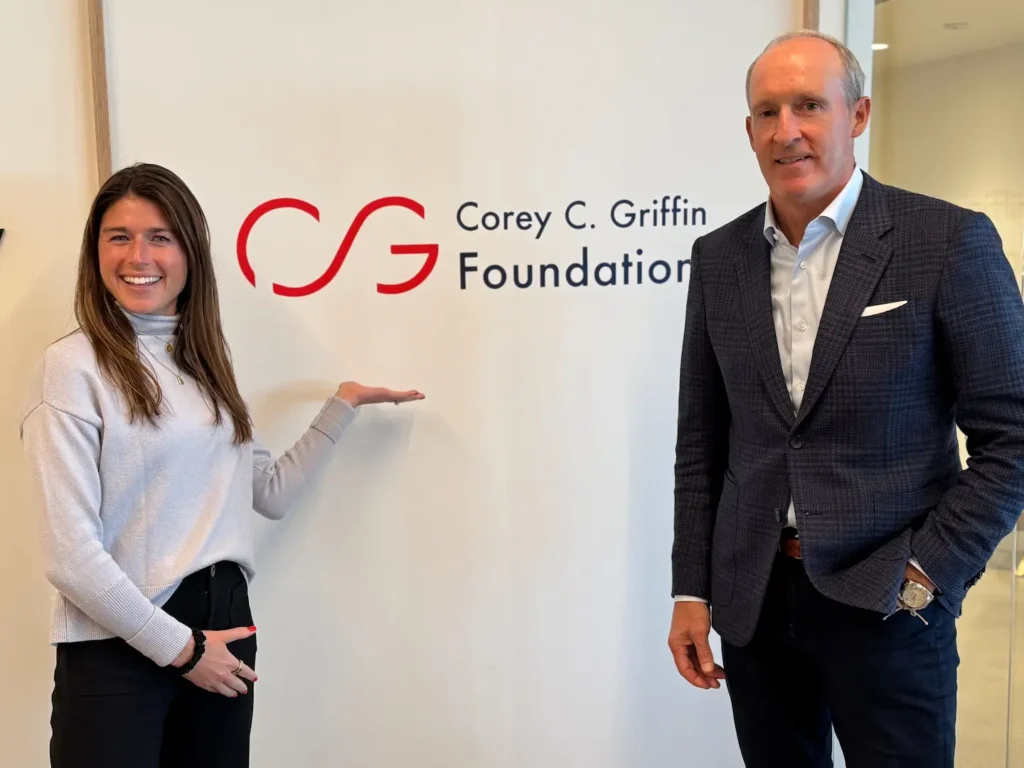 Casey Griffin Guidicelli and Joe Zink standing before the Foundation logo