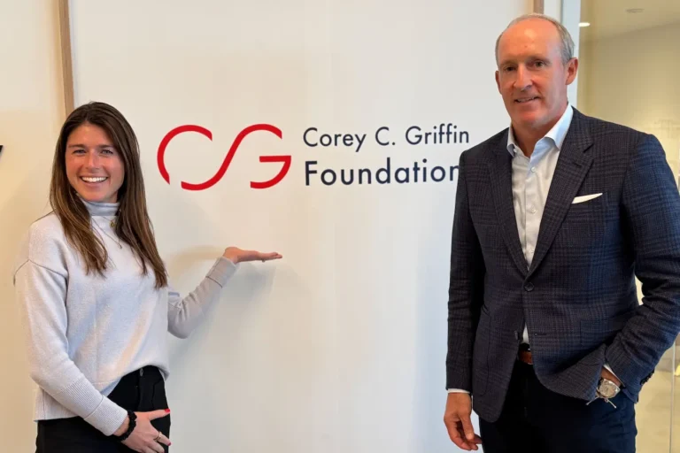 Casey and Joe standing before the Foundation logo