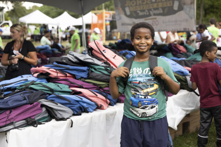 A student in front of a pile of new backpacks